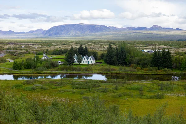 Beyaz İskandinav evlerinin panoramik görünümü, suda yansıması, bulutlu havalarda tepeler 
