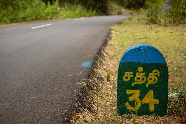 Belle route Ghat avec Milestone indiquant la distance à Sathyamangalam (en tamoul) le long de la chaîne de montagnes de Talamalai Reserve Forest, Hasanur, Tamil Nadu - frontière de l'État du Karnataka, Inde — Photo