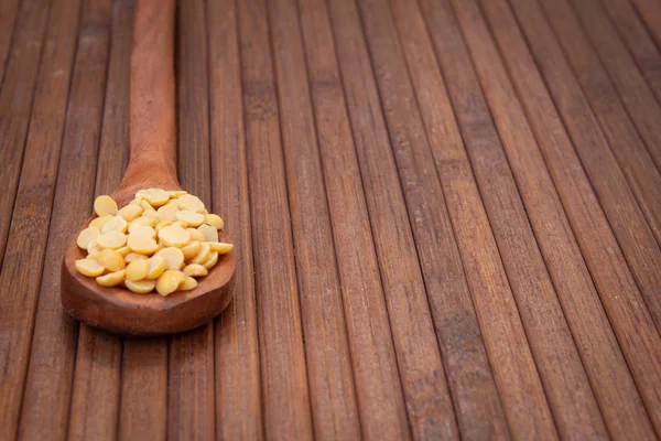 Picture of pigeon pea also known as toor dal in a wooden spoon. Isolated on brown background.