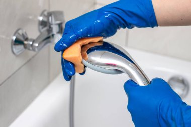 Kireç kireç, beyaz tebeşir tortu ve lekeler ticari bir sabun çıkarıcı kullanarak duş musluk ve duş başlığı temizleme sürecinin yakın çekim. Banyo temizliği ve dezenfeksiyonu