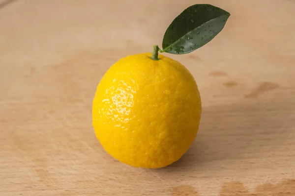 Frutto lacerato di un limone Volkamer con una piccola foglia verde su un legno — Foto Stock