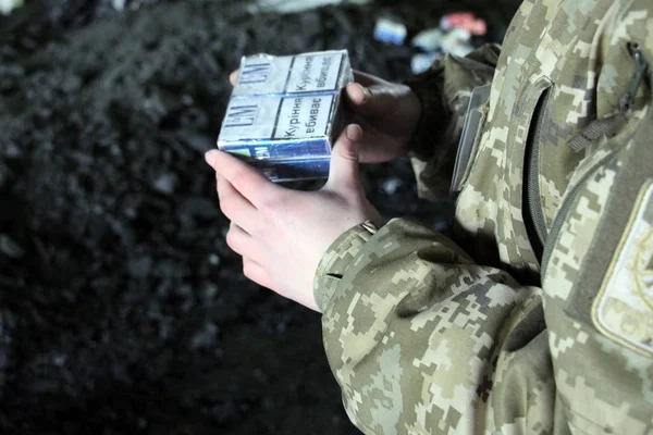 O guarda de fronteira em uniforme de camuflagem detém cigarro de contrabando — Fotografia de Stock