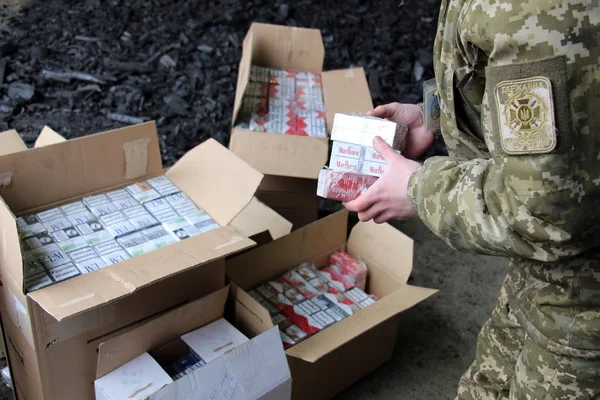 Le garde-frontière en uniforme de camouflage met des cigarettes de contrebande — Photo