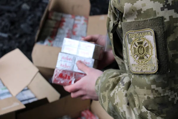 O guarda de fronteira em uniformes de camuflagem coloca cigarros contrabandeados — Fotografia de Stock