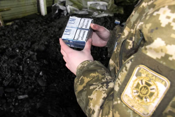 El guardia fronterizo en uniforme de camuflaje sostiene el contrabando de cigarrillos — Foto de Stock