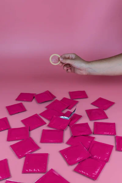 Молода Жінка Тримає Відкритий Презерватив Рожевому Тлі Рожевими Презервативами Столі — стокове фото