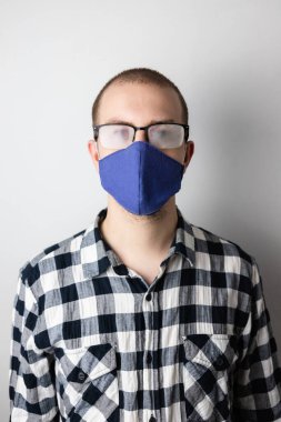 Koruyucu maske takan ve sis gözlüklü bir adam. Covid-19 salgını sırasında yeni alışkanlıklar. Sıcak nefes bardakları sisler.