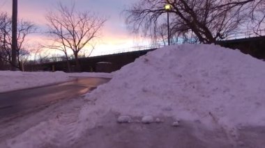 Pembe günbatımında insansız hava aracı demir yolu köprüsünden havalanıyor ve yükseliyor.