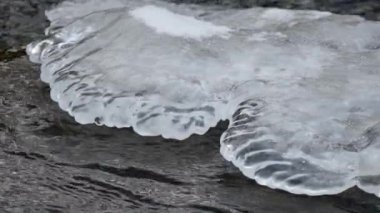 Karanlık nehir suyu kabarcıkları buzdaki siyah gölgelerin serin şekillerini oluşturur.