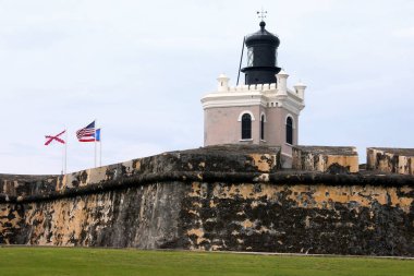 San Juan, Porto Riko'da kale duvarında eski deniz feneri ve üç bayrak