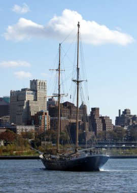 Ön planda East River üzerinde uzun bir gemi ile Brooklyn silueti