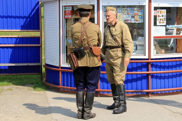 Living history event. Re-enactors in WWII Red Army military uniforms standing in front of a souvenirs kiosk. Minsk, Belarus