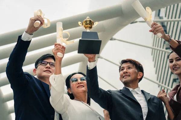 Asiatiska affärsfolk höjer händerna Holding Trophy och Winner cert — Stockfoto