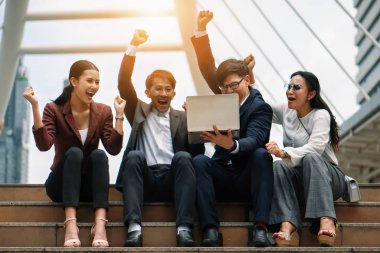 dizüstü bilgisayar ile asyalı iş adamları yumrukları yükselterek heyecan gösteren