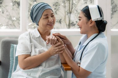asyalı hemşire nazikçe başlarını giyen üst düzey kanser hastası sarılmak