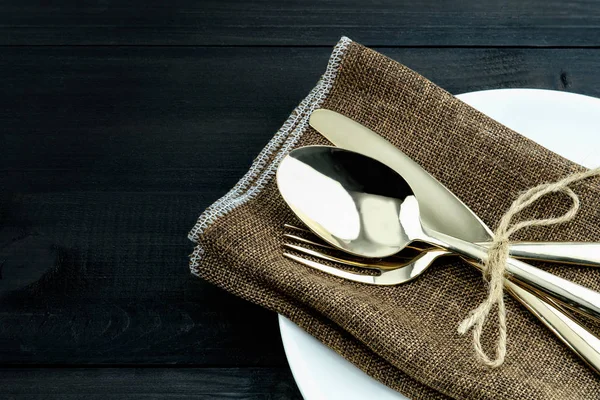 A set of bronze cutlery, spoon, fork and knife arrange on napkin