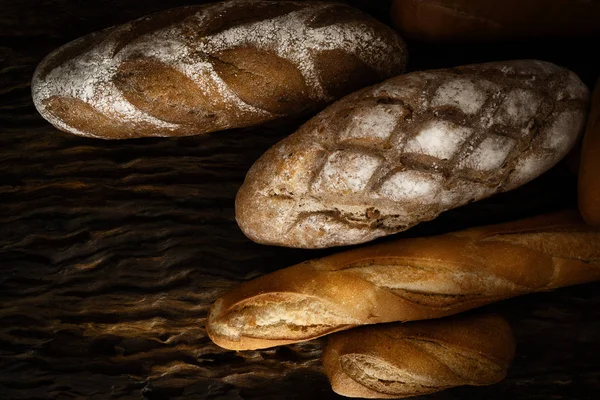 Різноманітні види хліба на дерев'яній дошці в темний тон — стокове фото