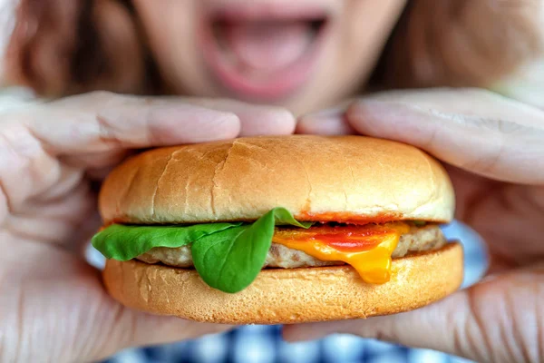 hamburgers being hold with hands of woman who in blurred backgro