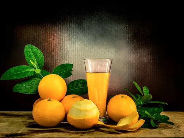 Un vaso de jugo de naranja con las naranjas frescas . — Foto de Stock