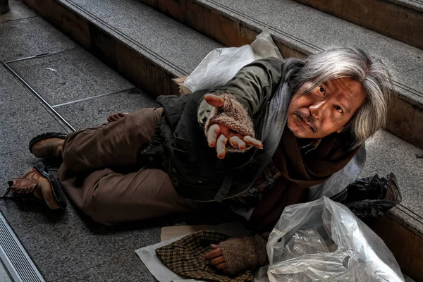 Homeless male showing hand asking for food or money while laying — Stock Photo, Image