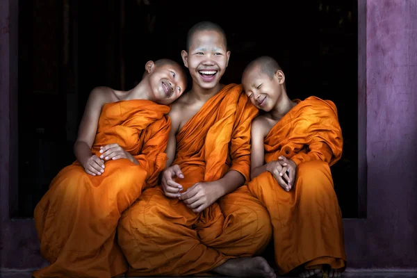 Three Thai Buddhist novices sitting together at temple door feel — Stock Photo, Image