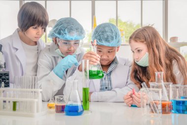 Beyaz ve Asyalı öğrenciler sci kimya deneyleri yapıyor