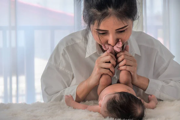 Asyalı anne elinde bebeğinin ayakları tutun — Stok fotoğraf