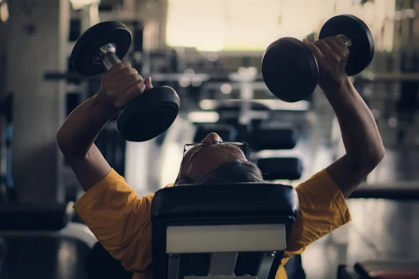 Senior masculino ejercitando levantando mancuernas en gimnasio — Foto de Stock