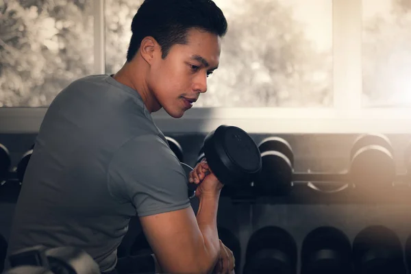 Macho teniendo ejercicio levantamiento mancuerna en gimnasio — Foto de Stock