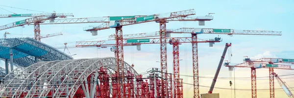 Tower cranes in operation at construction site with background o