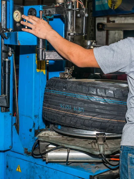 Mecánico que utiliza la estación de montaje de la rueda para ajustar el neumático nuevo al whee — Foto de Stock