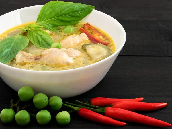 Siyah ahşap masa üzerinde beyaz kase tavuk yeşil köri, bir tradi