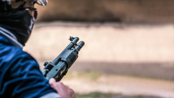 Mężczyzna trzyma strzelbę w trybie gotowości, aby strzelać w strzelance — Zdjęcie stockowe