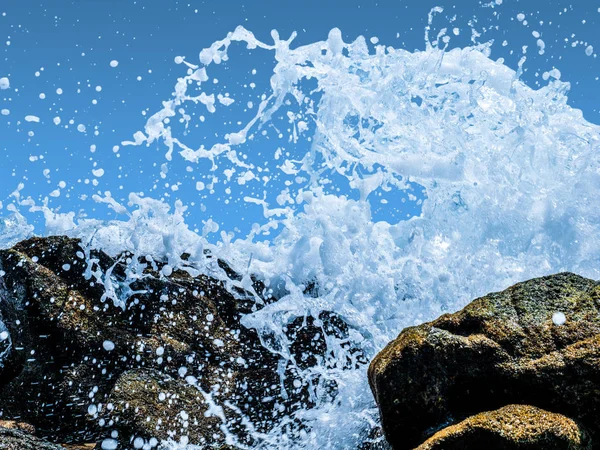Νερό που πιτσιλίζει στο βράχο του θαλάσσιου κύματος απομονωμένο σε μπλε φόντο — Φωτογραφία Αρχείου