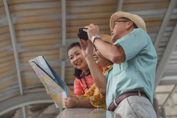 Group of chinese asian friends tourists with map on hands having — Stock Photo, Image