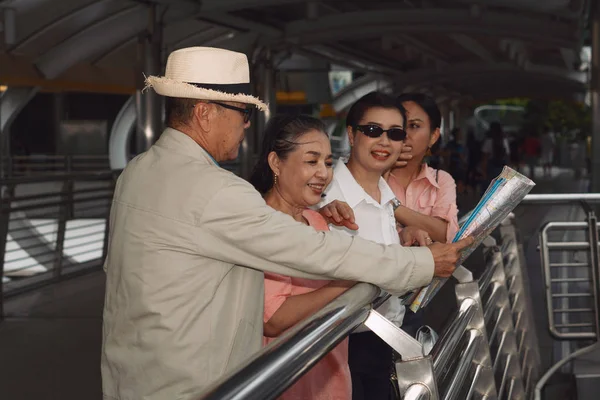 group of chinese asian friends tourists with map on hands having