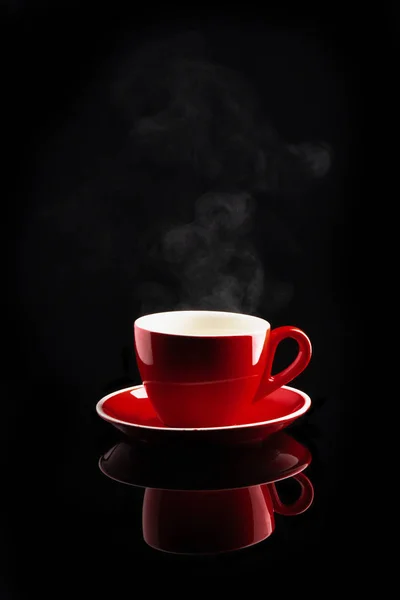 Steaming coffee or tea in red cup with reflection on dark backgr — Stock Photo, Image