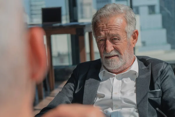 portrait of senior businessman with beard in business suit havin