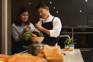 Genç Asyalı çift, Coronavirus salgını sırasında romantik ve eğlenceli anlar yaşıyor. Evde birlikte yemek pişiriyorlar.
