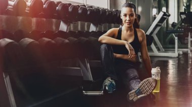 Beyaz kadın spor yaptıktan sonra dinleniyor ve spor ve spor salonunda egzersiz yapıyor. Sallanan dambıllar, sağlıklı spor kadın yaşam tarzı.