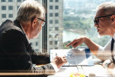 İki Kafkasyalı iş adamı iş stratejisi için iş görüşmesi yapıyorlar iş merkezindeki iş salonundaki masada iş belgeleriyle birlikte, seçici bir şekilde odaklanmış.