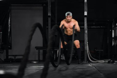 Asyalı atletizm vücut geliştirici spor salonu ve spor salonunda halatla antrenman ve egzersiz.