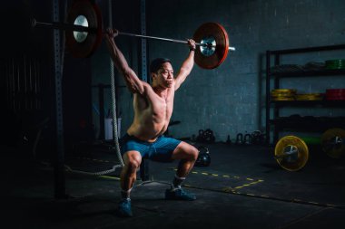 Asyalı güçlü adam spor salonunda ve spor salonunda ağırlık kaldırıyor.