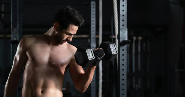 shirtless caucasian athletics bodybuilder man exercise with dumbbell lifting at gym and fitness club