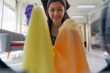 Asyalı ev kadını ev işi yapıyor ve temizlik için çamaşır makinesine havlu atıyor.