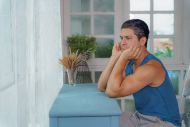 Kafkasyalı bir adam pencerenin kenarında oturmuş kendini izole ederken dışarıya bakıyor ve Coronavirus covid-19 salgını sırasında kilitleniyor.