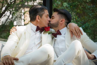 Beyaz takım elbiseli eşcinsel gelin ve damat LBGT düğün töreninde birlikte mutlular.