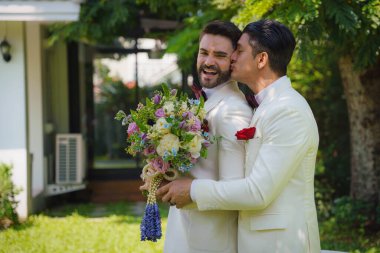 Beyaz takım elbiseli eşcinsel gelin ve damat LBGT 'nin düğün töreninde birlikte mutlular.