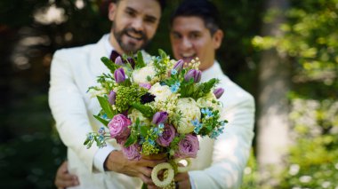Beyaz takım elbiseli eşcinsel gelin ve damat LBGT 'nin düğün töreninde birlikte mutlular.