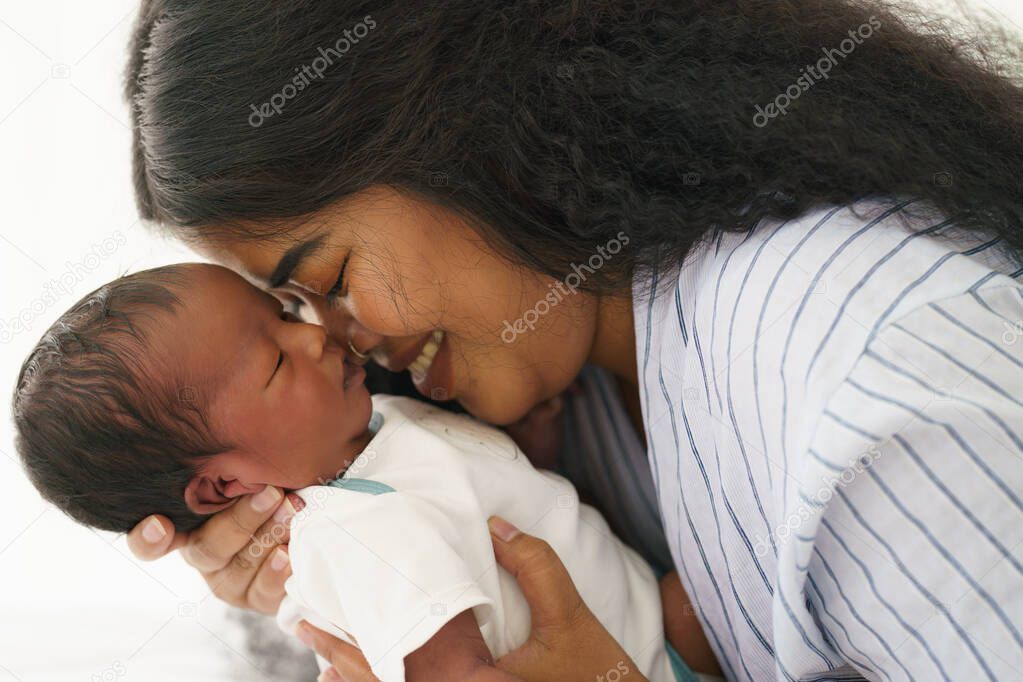 mixed race african american and asian mother holding her newborn baby with happy face